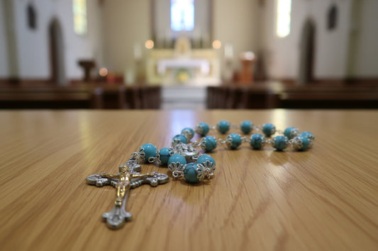 Rosary with blue beads and a gold and silver cross on a wooden surface